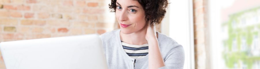 Woman looking at computer screen in front of brick-lined wall
