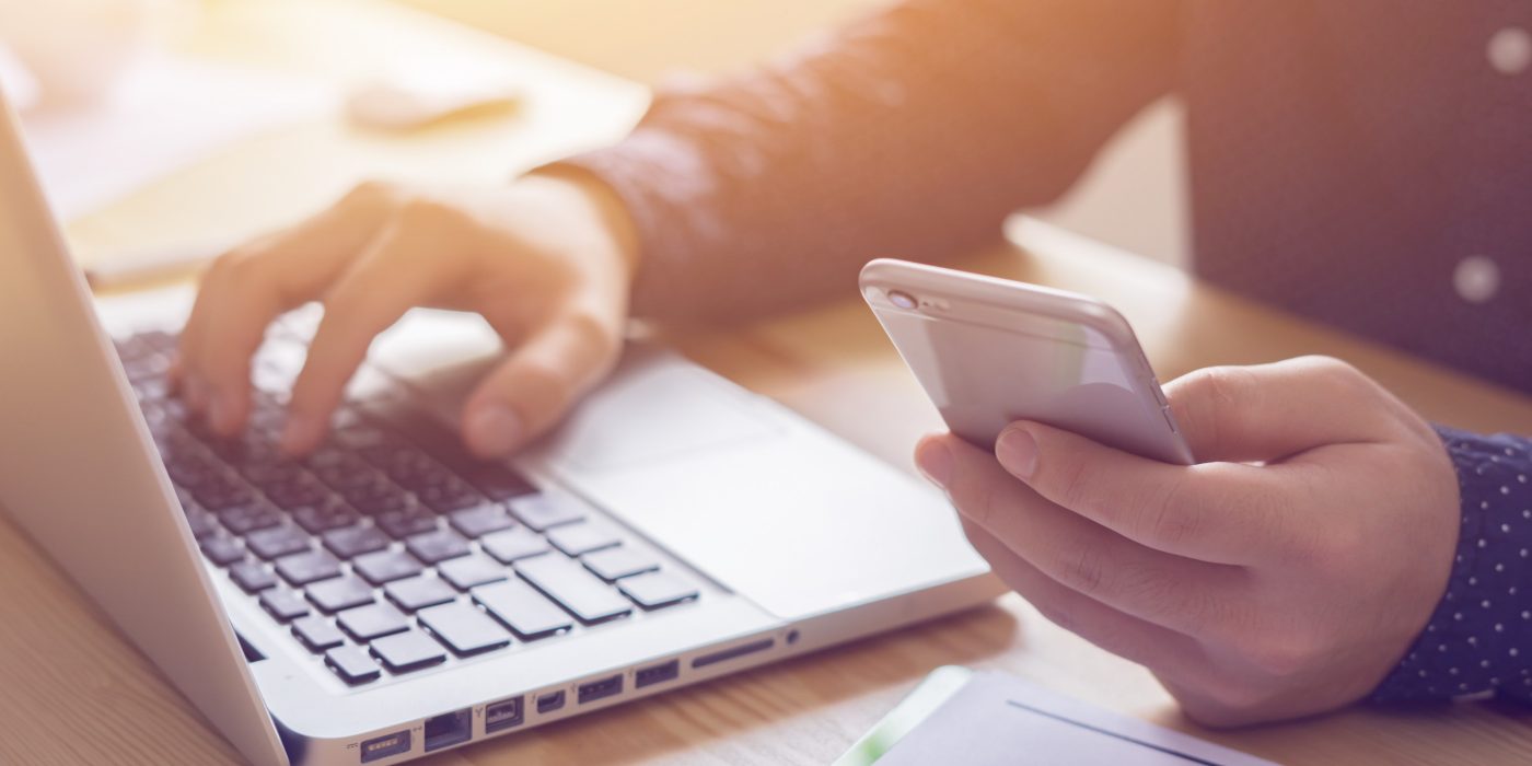Young man working with iPhone and Laptop